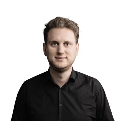 Junger Mann mit blondem Haar und schwarzem Hemd vor weißem Hintergrund